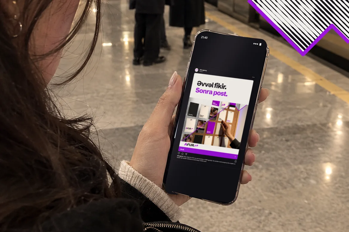 Bakı metrosunda qadın telefonda AFUR-⁠un reklamına baxır: “Əvvəl fikir. Sonra post.” Qatarın qapıları açıqdır.
